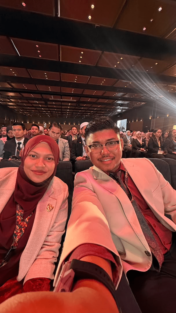 Selfie Syarif Jamil (SJ) dan Puan Syamimi mengenakan lencana emas Public Gold di dalam dewan konvensyen Master Dealer Conference (MDC)
